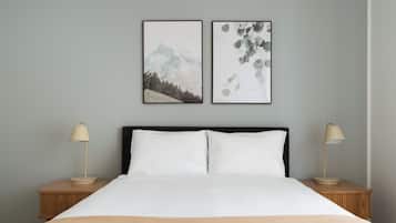 A bed with white bedding, two bedside lamps, and two framed pictures on the wall.