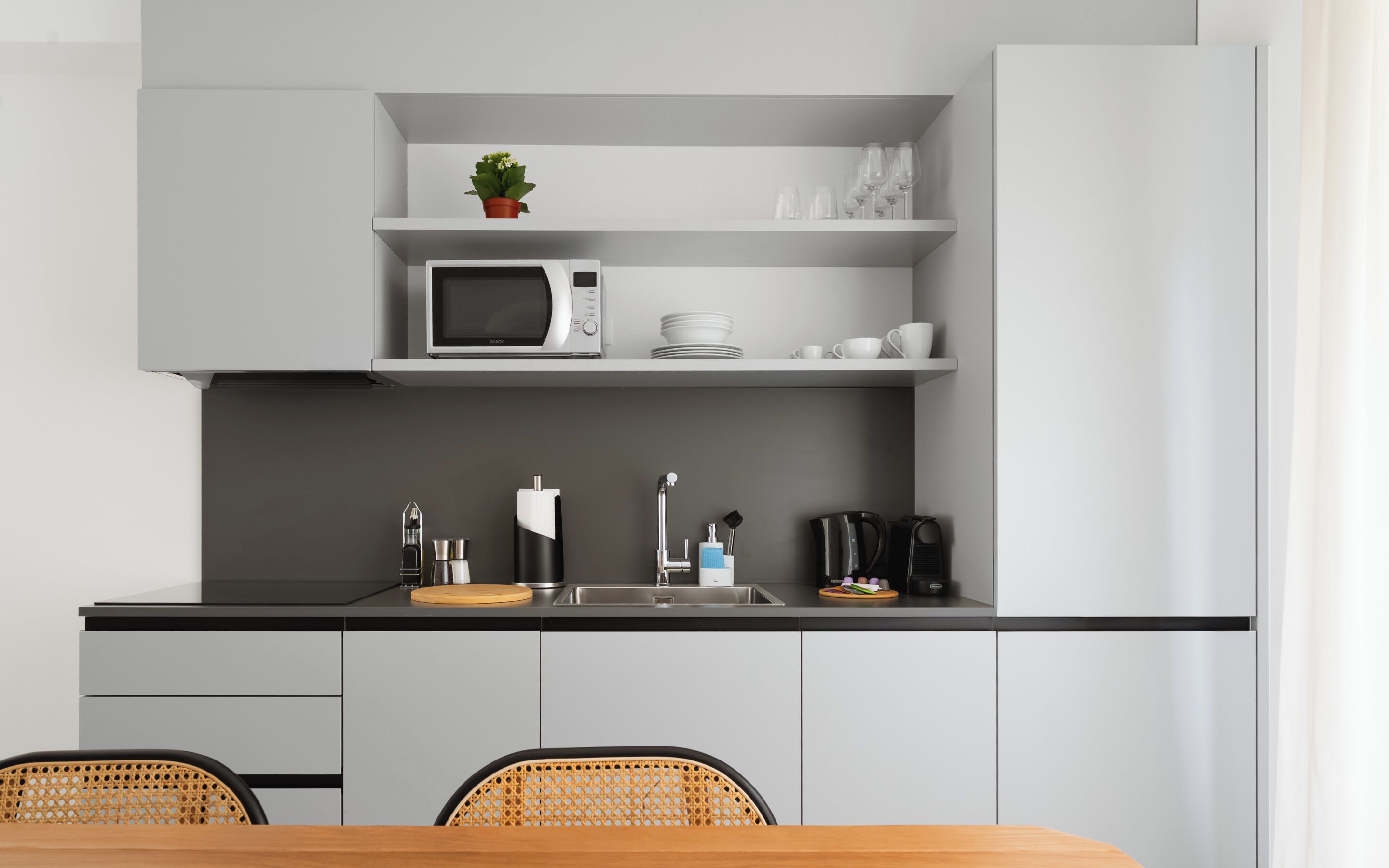 Eine moderne Küche mit Mikrowelle, Spüle und Essbereich mit Stühlen.