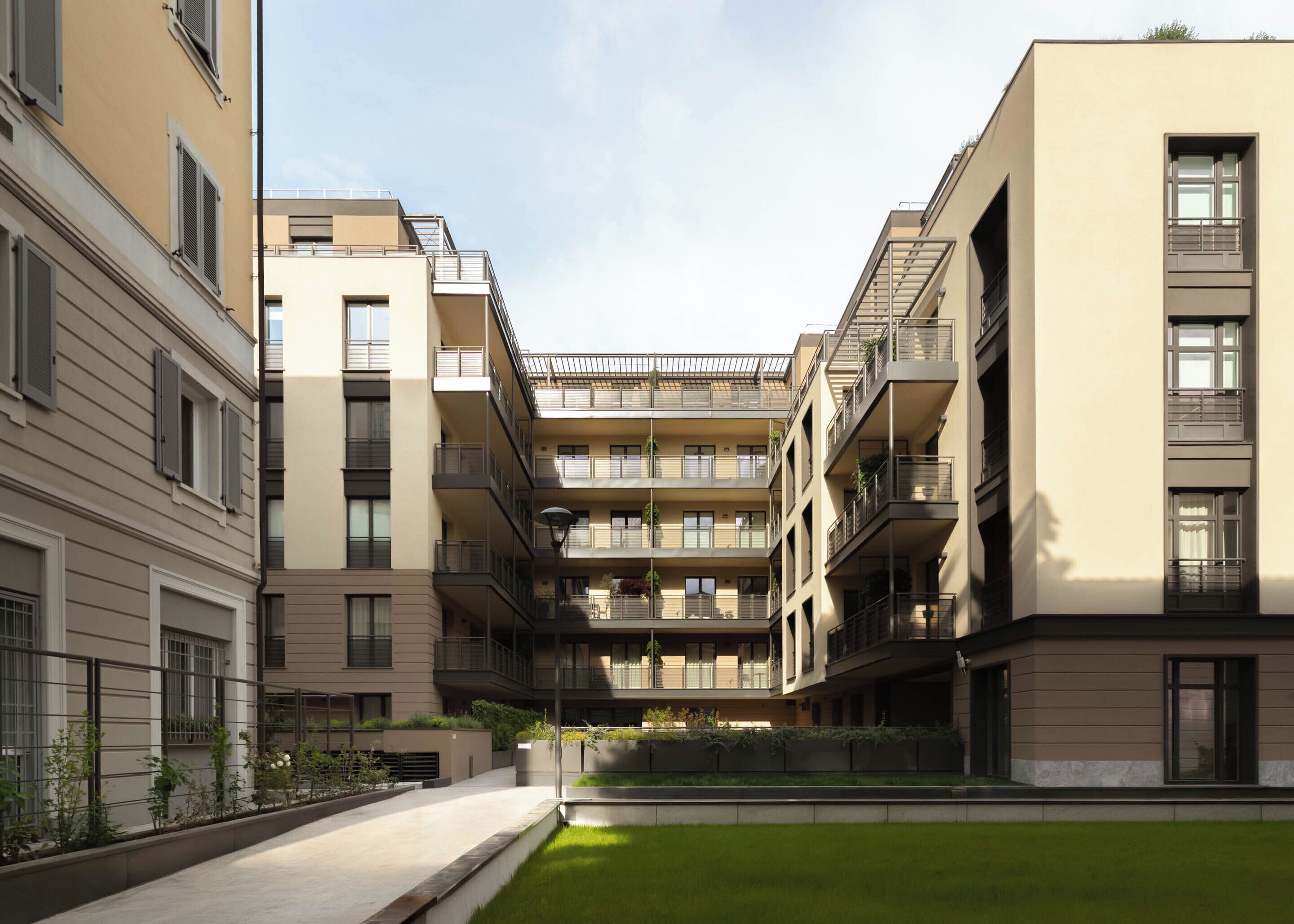 Een meerlaags woongebouw met balkons, een centrale binnentuin en een plat dak.