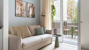 A living room with a sofa, a small table, and a balcony with outdoor furniture.