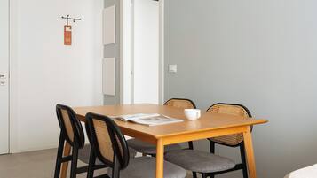 A dining area with a wooden table, six chairs, a hanging light fixture, and a door with a sign.