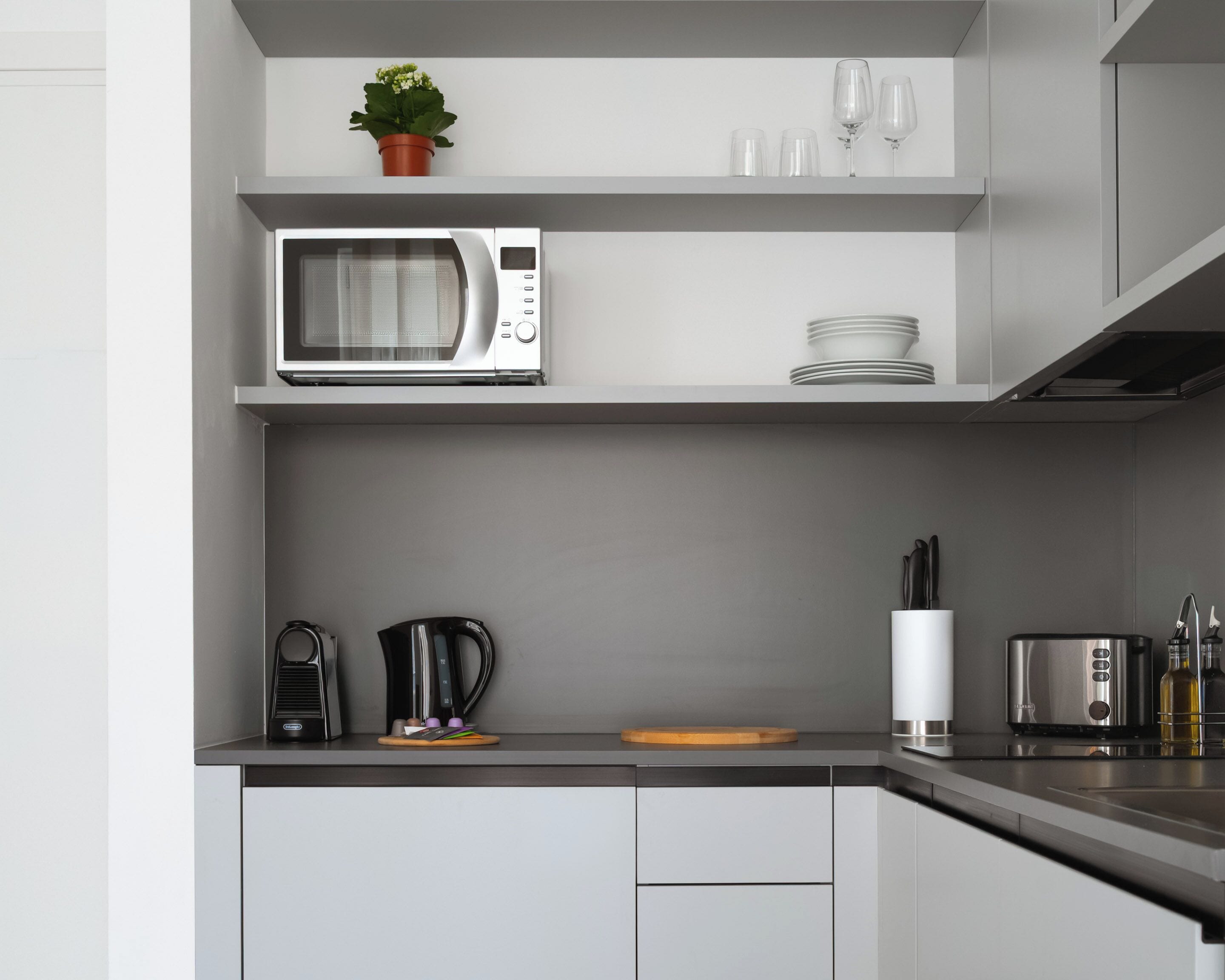 A modern kitchen with a built-in microwave, coffee maker, and a knife block.