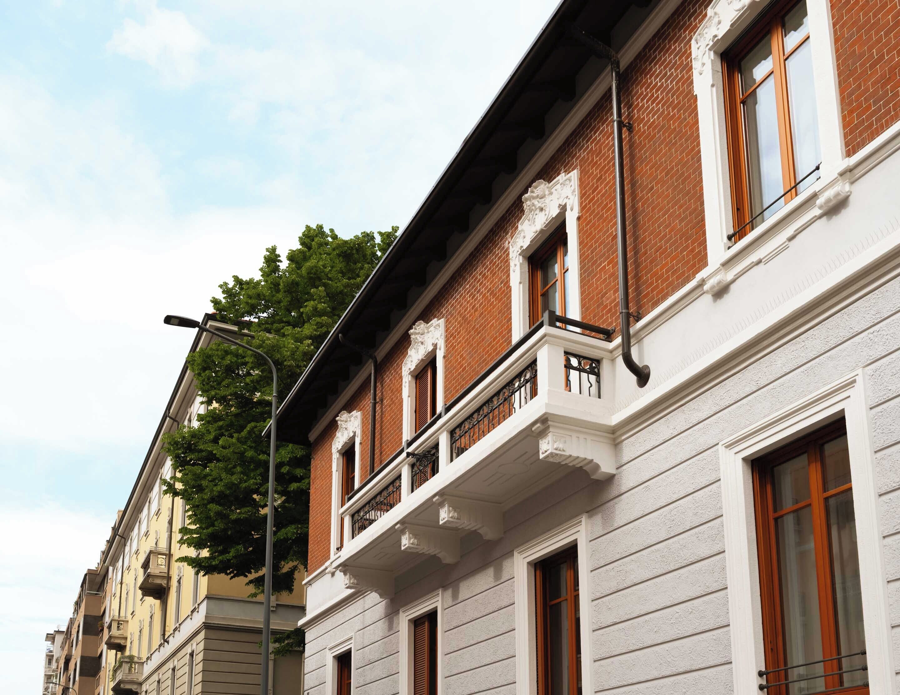 A multi-story building with a brick facade, white trim, and multiple windows.