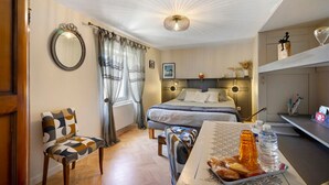 Un dormitorio con cama, una silla, un escritorio con cosas para el desayuno y un espejo en la pared.
