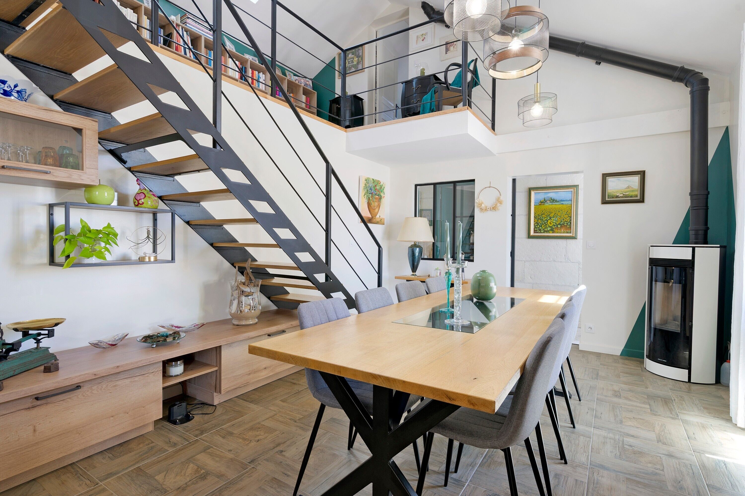 Une cuisine moderne dotée d’un îlot central, d’un coin repas avec une grande table et d’un escalier menant à un niveau supérieur.