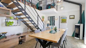 Une cuisine moderne dotée d’un îlot central, d’un coin repas avec une grande table et d’un escalier menant à un niveau supérieur.