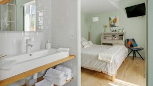 Une salle de bain moderne avec un grand lavabo blanc, un miroir et des étagères en bois où sont posées des serviettes.