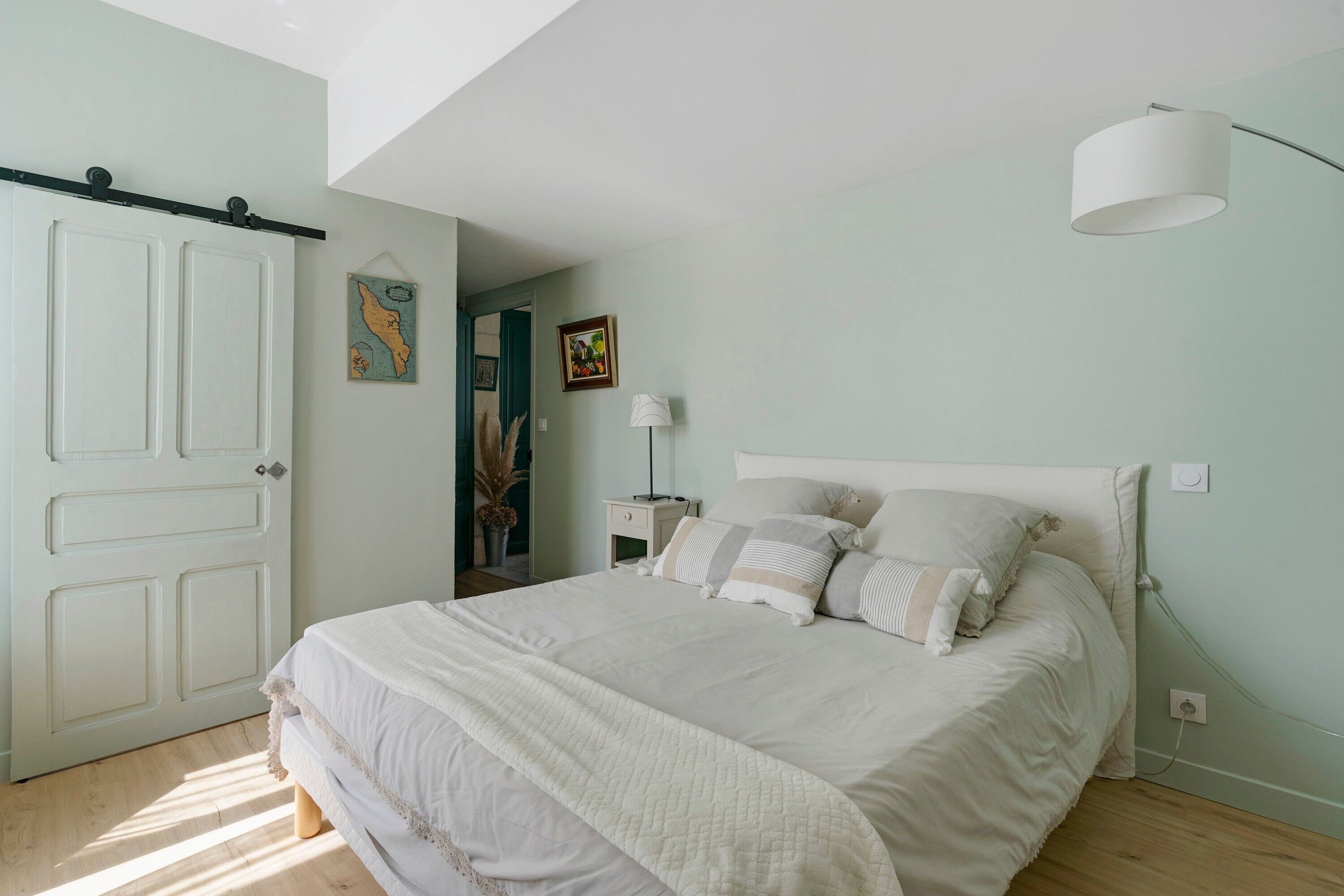 A bedroom with a bed, a nightstand, a lamp, and a door.