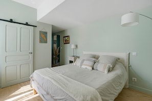 Une chambre à coucher avec un lit, une table de chevet, une lampe et une porte.