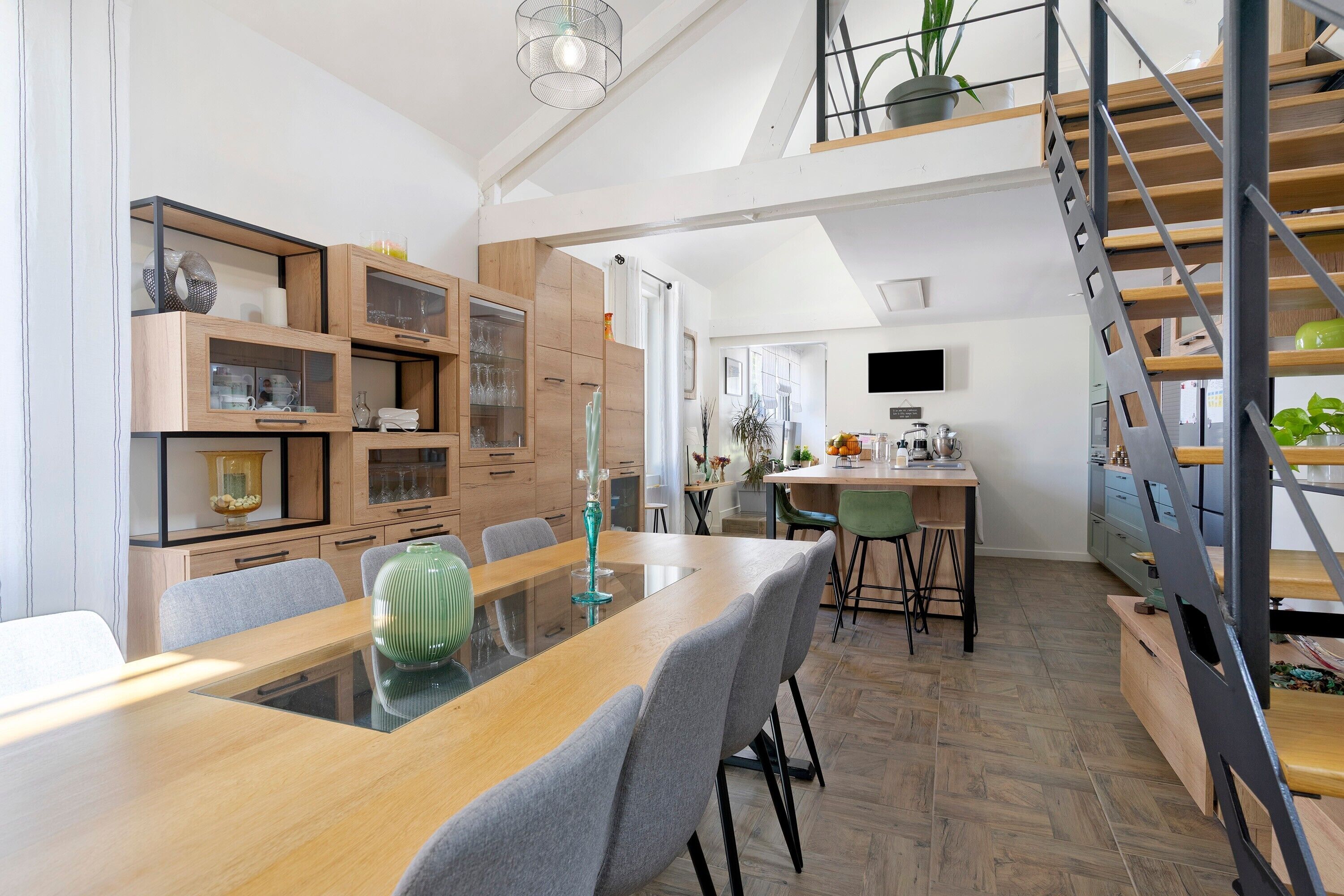 Una cocina moderna con armarios de madera, una mesa de comedor y una escalera.