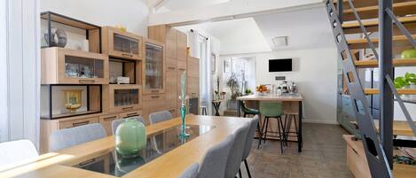 Una cocina moderna con armarios de madera, una mesa de comedor y una escalera.