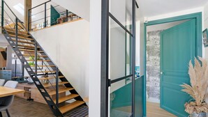 Un intérieur moderne avec un escalier en bois, une porte en verre et une porte de couleur turquoise.