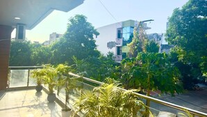 Ein Balkon mit Blumentöpfen, einer Brüstung und Blick auf Gebäude und Bäume.