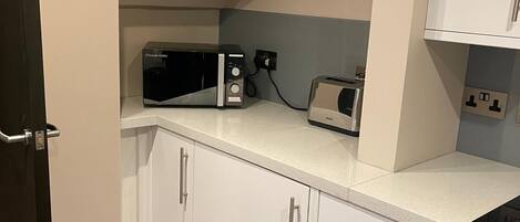 Una cocina con armarios blancos, un microondas, un tostador y un lavavajillas.