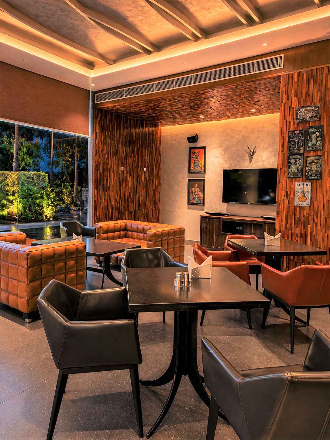 A modern interior with a sectional sofa, dining table, and chairs, a flat-screen TV, and a wall with framed pictures.