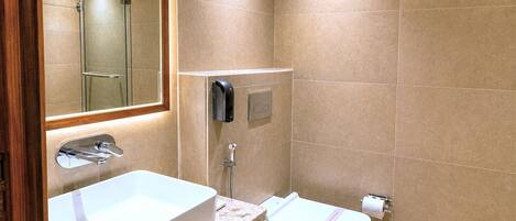 A modern bathroom with a large sink, a toilet, a glass shower enclosure, and a mirror.