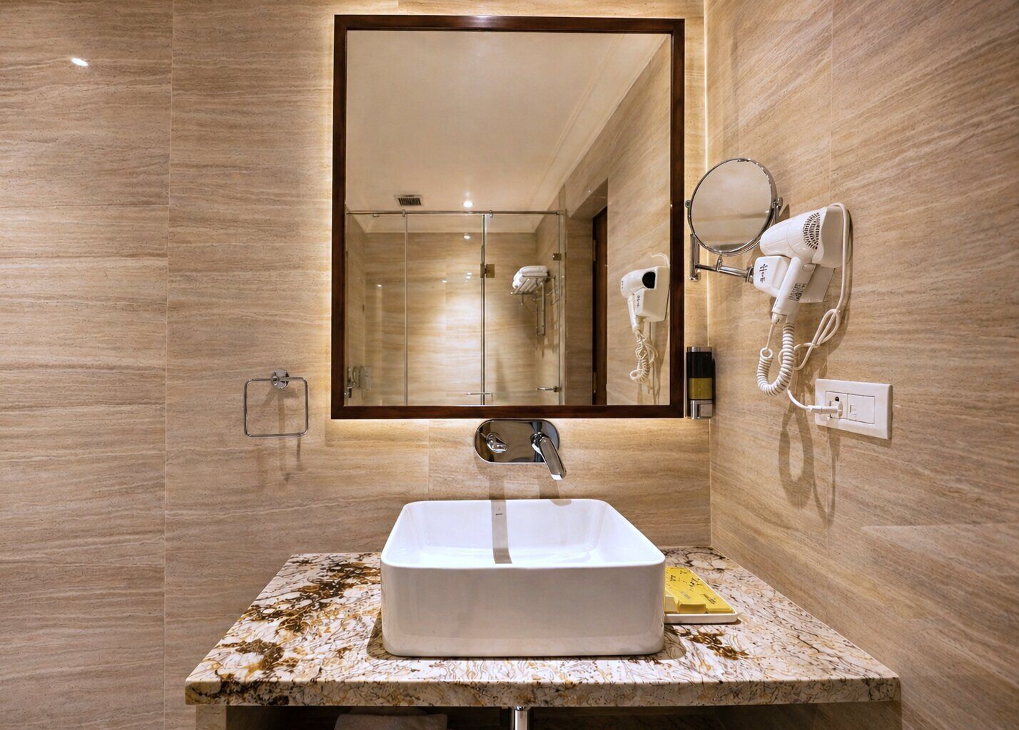 A bathroom with a marble countertop, a white sink, a mirror, a hairdryer, and a telephone.