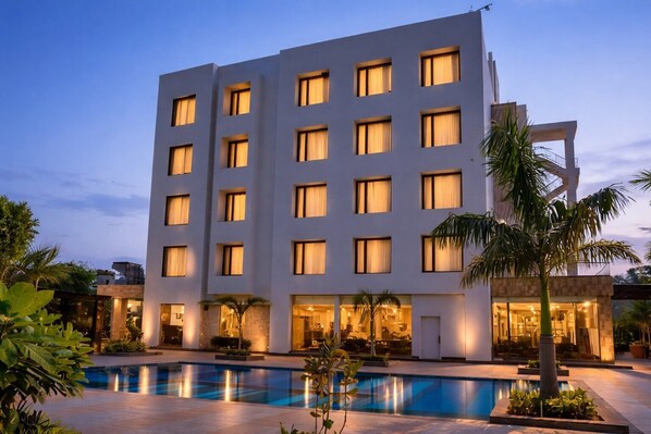 A modern hotel with a pool, multiple floors, and a well-lit facade. - Hillcrest Hotel & Resort (Abu Road)