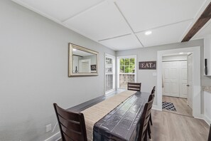 Un espace repas avec une longue table, des chaises, un miroir et un panneau indiquant « MANGER ».