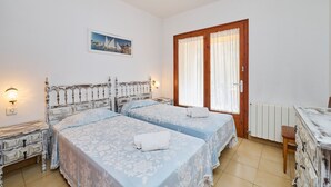Een slaapkamer met twee bedden, een houten hoofdbord, een nachtkastje, een tafel en een stoel.
