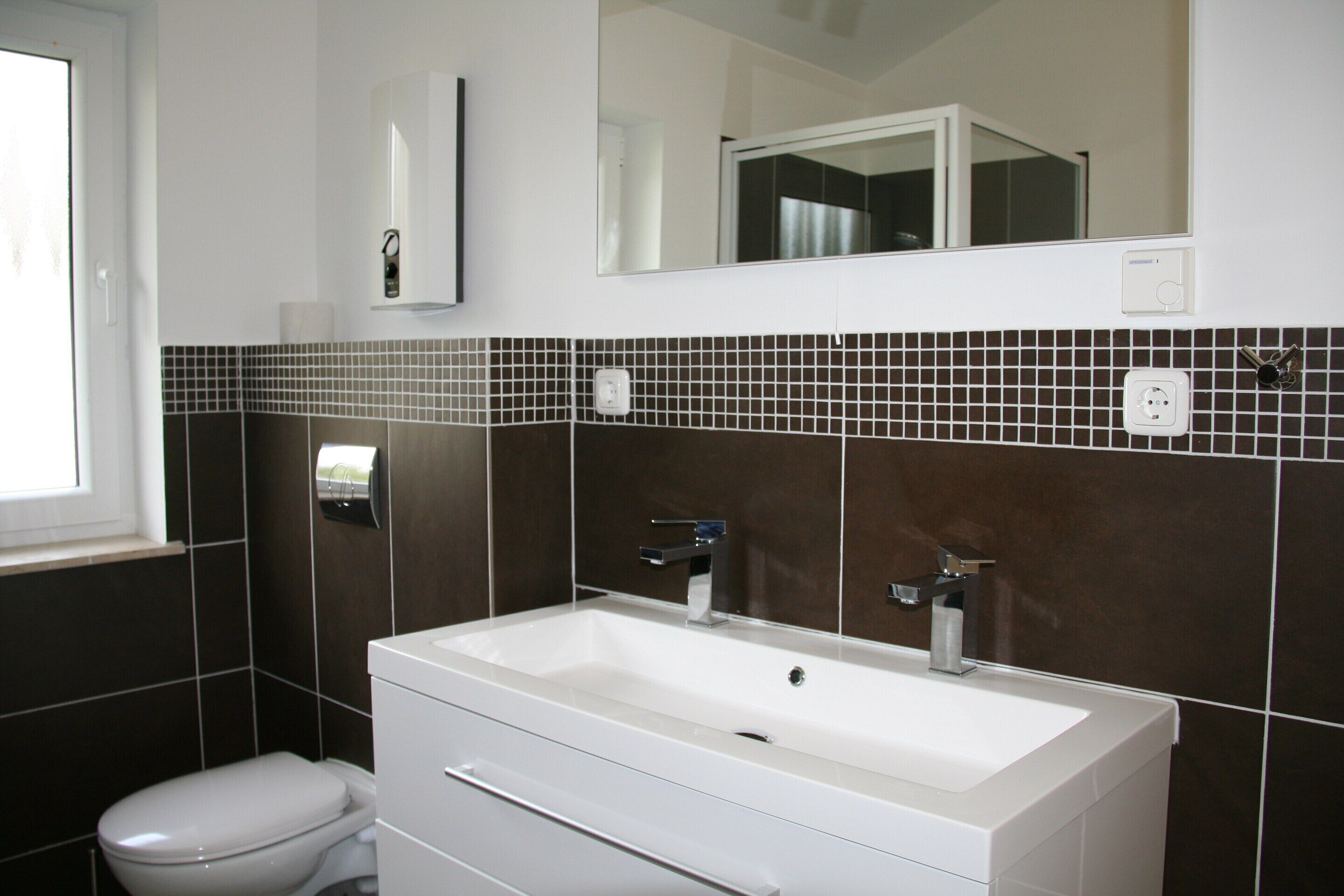 A modern bathroom with a large rectangular sink, a toilet, and a mirror above the sink.