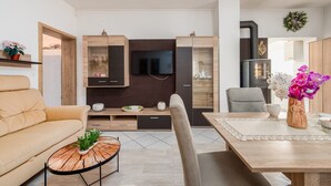 Ein modernes Wohnzimmer mit einer Couch, einem Couchtisch, einem Fernseher, Holzkredenz und einem Kamin.