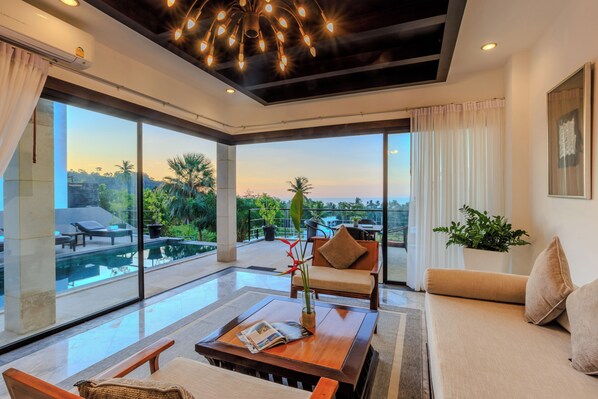 A modern living room with a large glass wall, a pool, and a view of the outdoors. - ediResidences Family Pool Villa w/ Ocean View (Koh Samui)