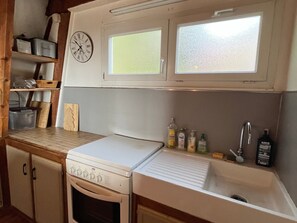 A kitchen with a clock, a sink, and cabinets.
