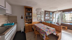 Uma cozinha compacta com área de refeições, armários de madeira, micro-ondas e uma janela com vista.