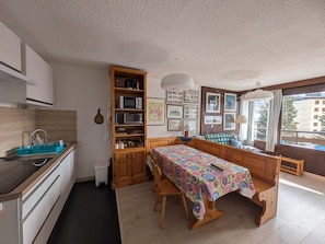 Une cuisine compacte avec un coin repas, des placards en bois, un four à micro-ondes et une fenêtre donnant sur un beau paysage.