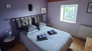 Een slaapkamer met een houten plafond, een bed met hoofdeinde, een raam en een radiator.