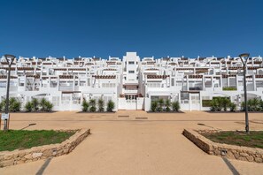 A modern building with a symmetrical facade, multiple balconies, and a central entrance.