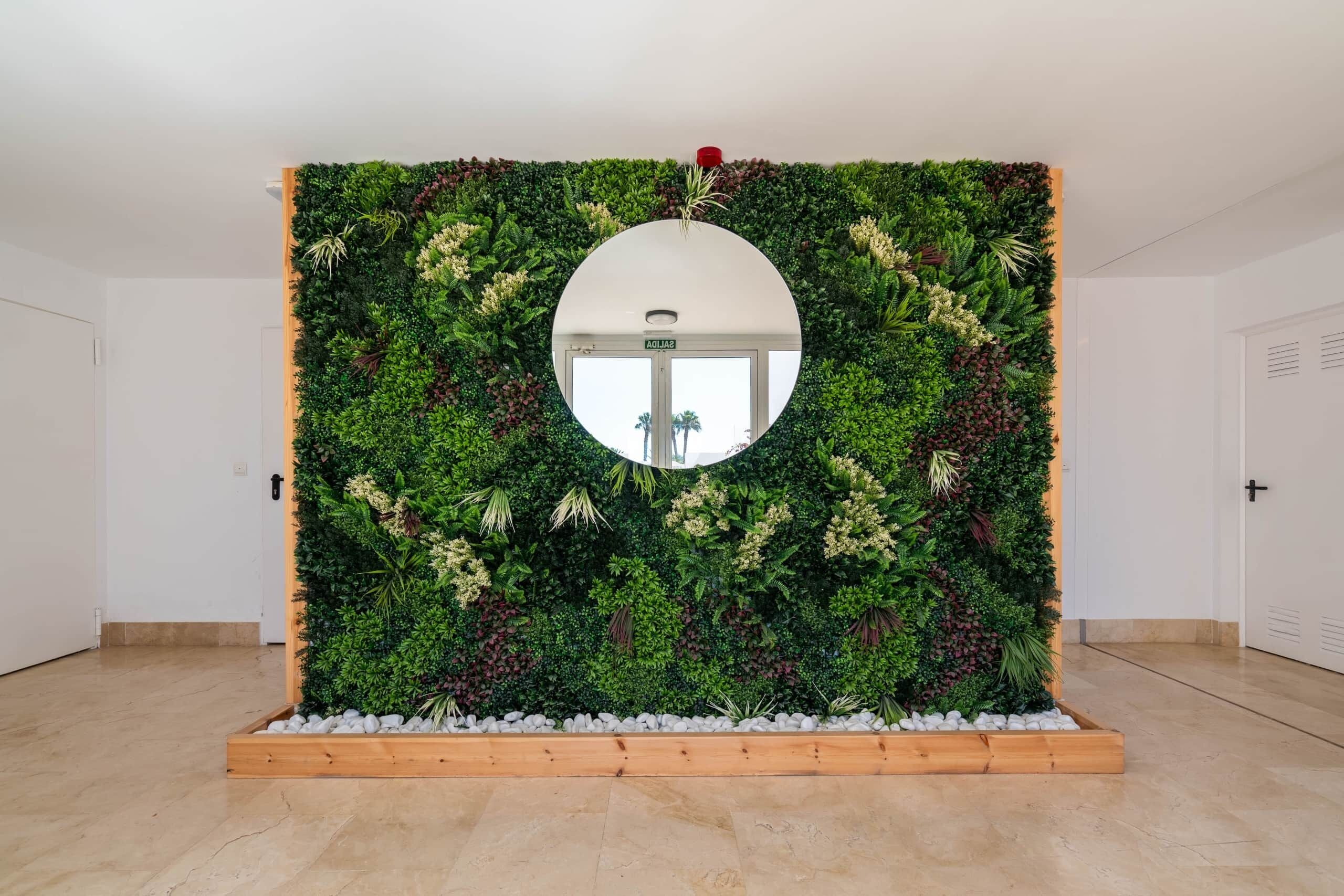 A room with a large mirror, a green vertical garden, and a wooden floor.