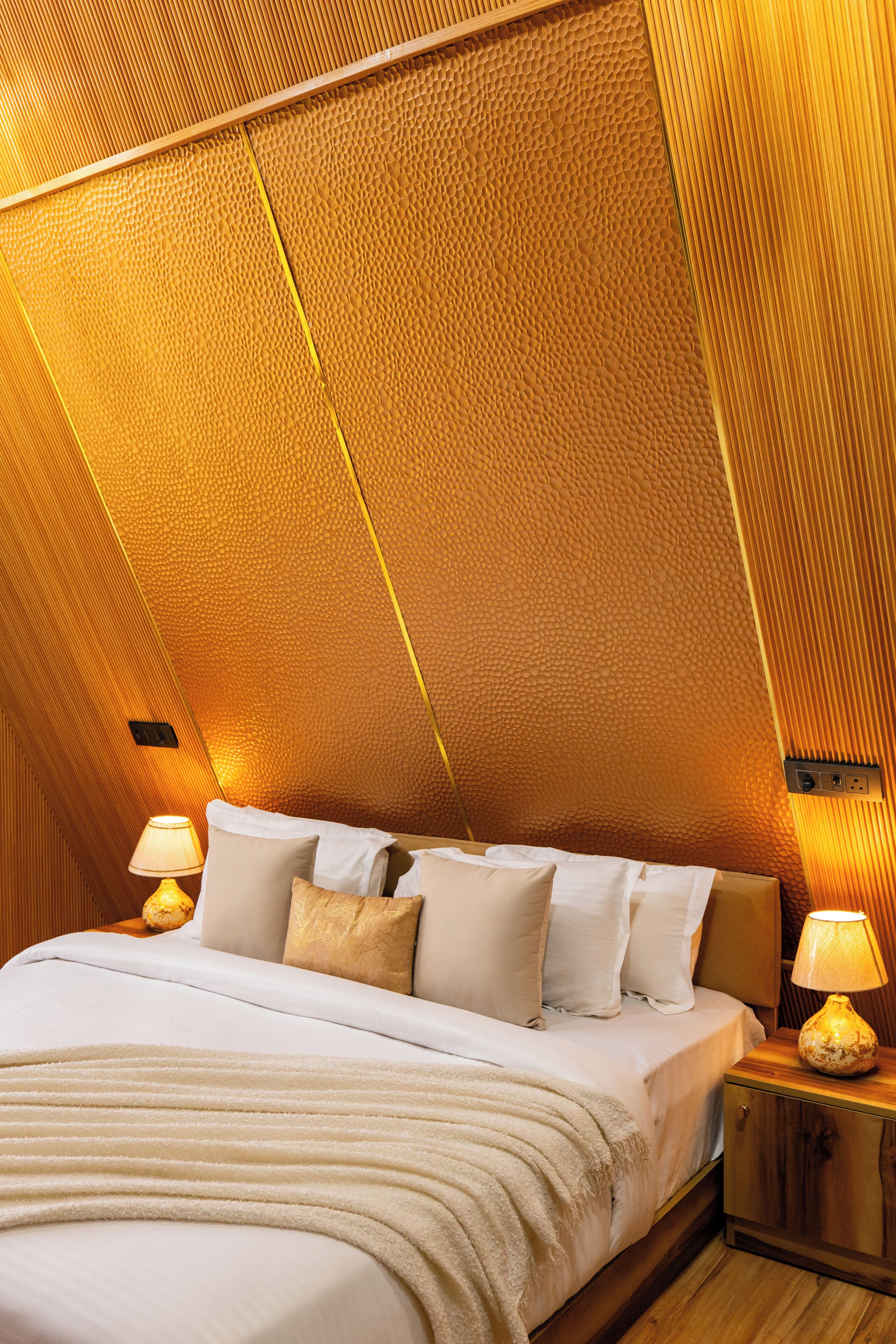 A bedroom with a sloped ceiling, a bed with white bedding, and two bedside lamps.