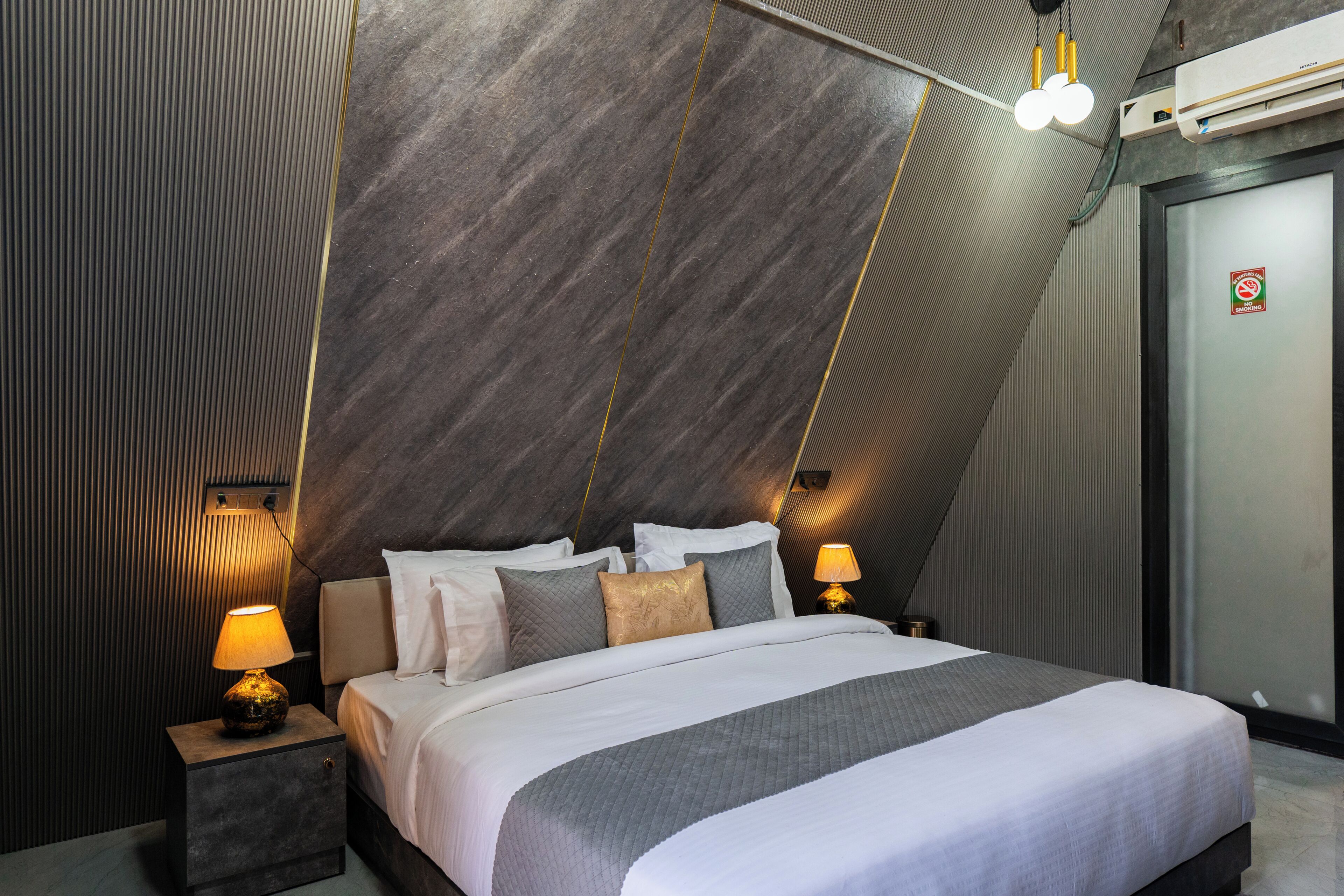 Ein modernes Hotelzimmer mit einem Bett, Nachttischlampen und einer Wandklimaanlage.