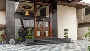 A modern building entrance with a checkered floor, a large wooden door, and a chandelier. - Innara - A Boutique Luxury Hotel (Jaipur)
