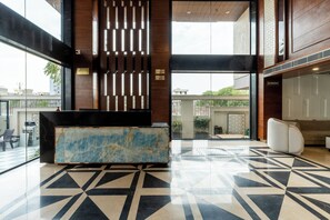Eine Lobby mit einer Rezeption, einem gemusterten Boden und Blick nach außen.