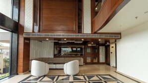 A lobby with a geometric patterned floor, a seating area with white chairs, and a view of a dining area. - Innara - A Boutique Luxury Hotel (Jaipur)