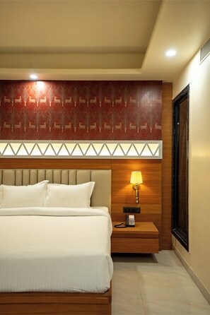 Ein Hotelzimmer mit einem großen Bett, einem Nachttisch mit Lampe, einer Wand mit Muster und einem hölzernen Kopfteil.