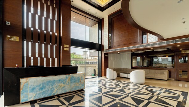 A reception area with a marble counter, a patterned floor, and a seating area with white sofas. - Innara - A Boutique Luxury Hotel (Jaipur)
