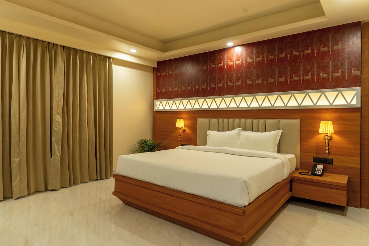 A hotel room with a large bed, wooden headboard, two bedside lamps, and a telephone on the nightstand.