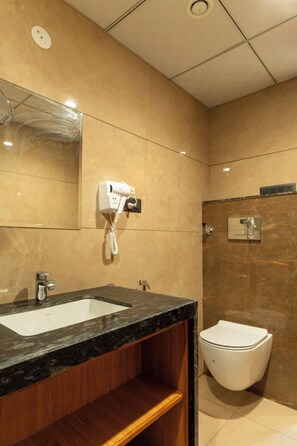 Ein Badezimmer mit Waschbecken, Spiegel, Fön und Toilette.