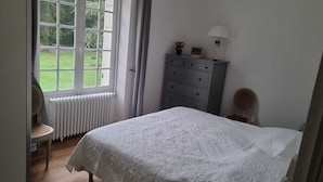 Makuuhuone, jossa on sänky, lipasto, tuoli, ikkuna ja patteri.