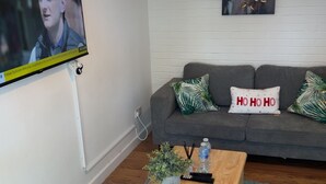 A living room with a TV, sofa, coffee table, and a painting on the wall. - Two bedrooms house with a work space (Basildon)