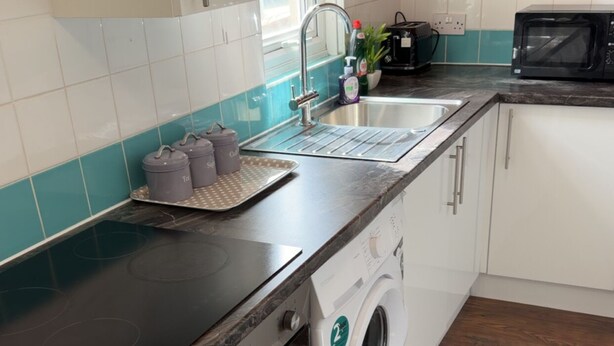 A kitchen with a washing machine, a microwave, and a sink. - Two bedrooms house with a work space (Basildon)
