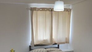 A bedroom with a bed, nightstand, lamp, curtains, and a rug. - Two bedrooms house with a work space (Basildon)
