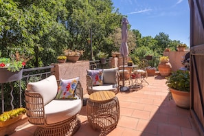 A patio with wicker furniture, potted plants, and a grill area.
