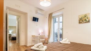 Une chambre d’hôtel équipée d’un lit, d’un bureau, d’une chaise, d’une télévision et d’un balcon avec vue.