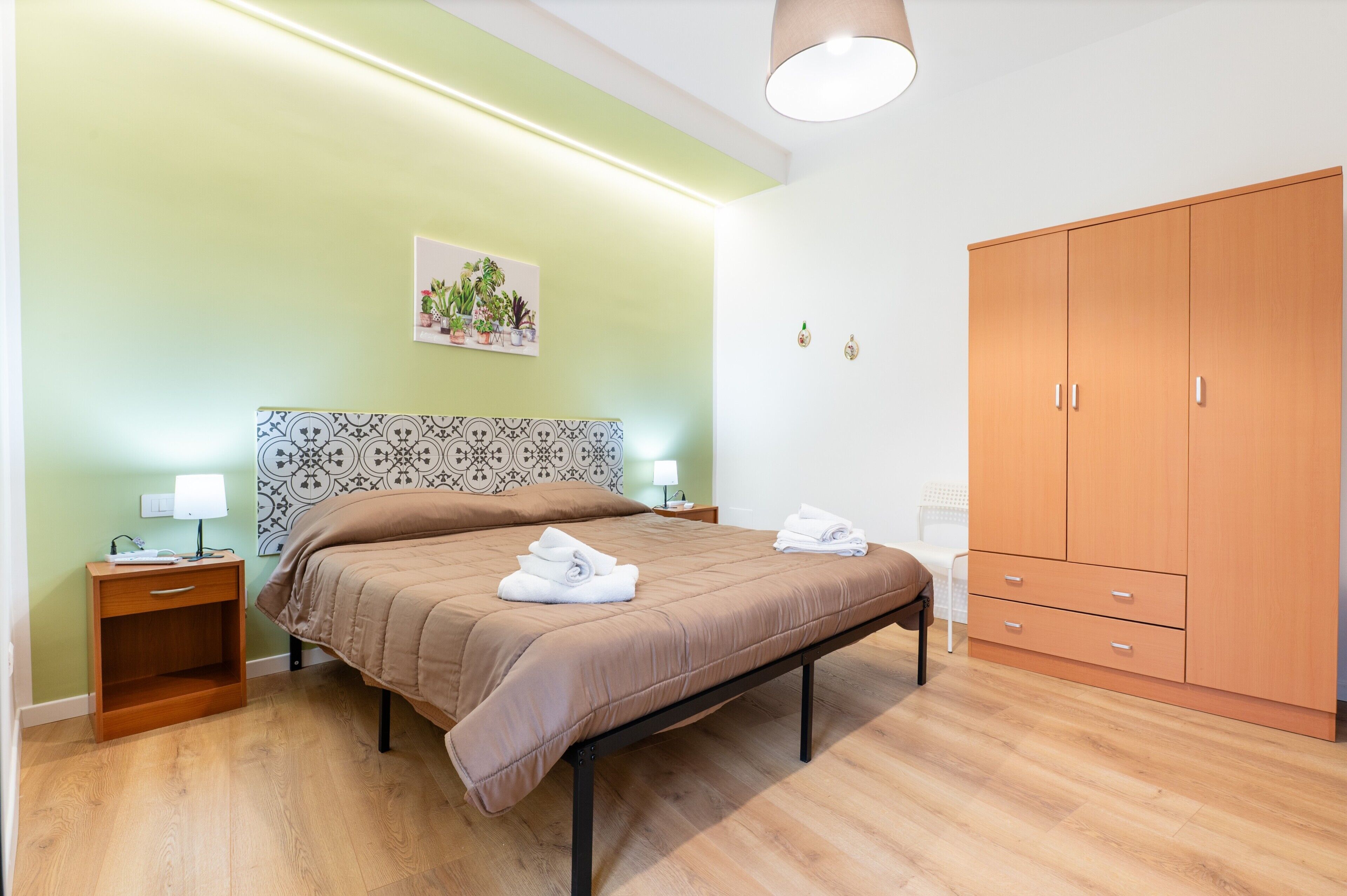 A bedroom with a bed, bedside tables, a wardrobe, and a wall-mounted artwork.