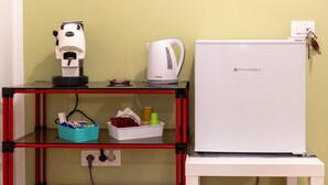 Une petite cuisine équipée d’une machine à café, d’une bouilloire et d’un réfrigérateur.